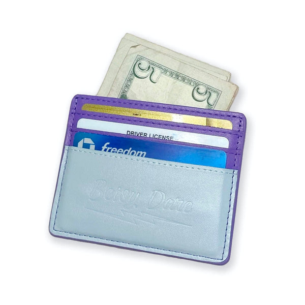 rectangular faux leather 6 slot card holder in bright purple and light blue with diagonal teal faux leather lightning bolt applique in middle. Shown from back with cards and cash