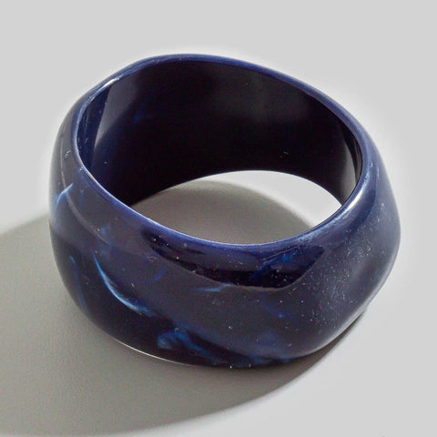 navy blue resin bangle in asymmetrical round shape with light blue and clear marbling