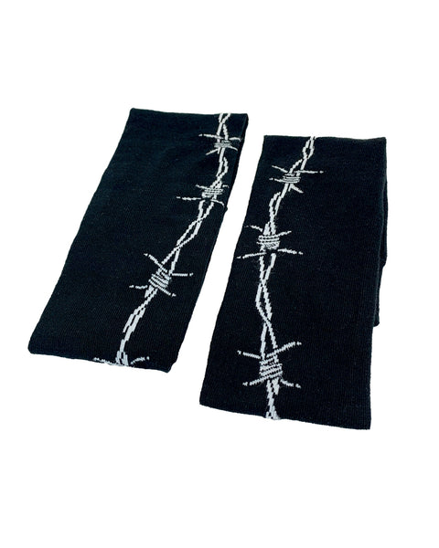 over-the-knee length socks in solid black cotton with white knit in pattern of barbed wire running down the outer leg of each sock, shown folded flat