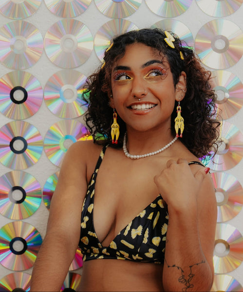 yellow marbled acetate dangle earrings in the shape of a pair of rubber chickens with red mouths, feet, and waddles with silver rhinestone jeweled necklaces. Shown worn by model