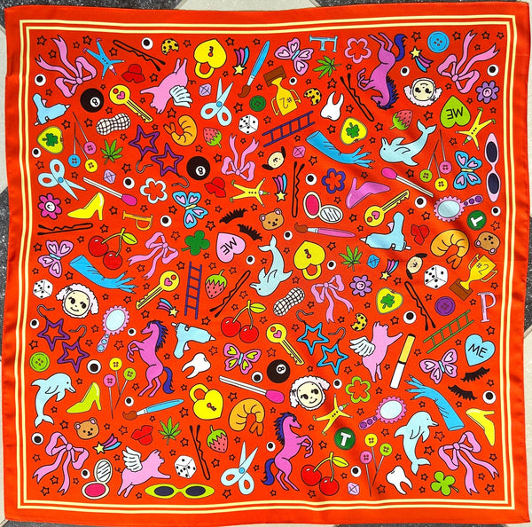 square satin twill scarf in bright red with yellow stripe border and all-over cartoon pattern of "junk drawer" items including bobby pins, heart locks, keys, dolphins, glue guns, shrimp, tiny cat-eye sunglasses, matches, buttons, and cigarettes. Shown flat