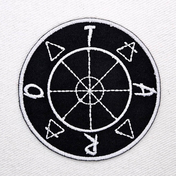 round black twill embroidered patch with white design of tarot wheel of fortune, element symbols, and letters spelling 'TAROT'. Shown flat