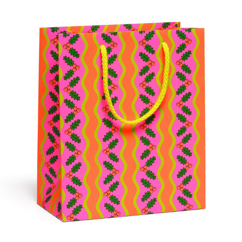 A gift bag with an allover print of vertical wavy stripes of red and green holly with wavy neon pink and green stripes on a neon orange background