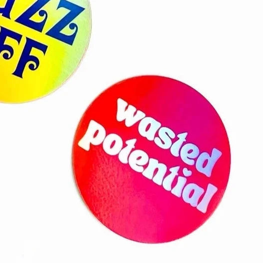 3” round holographic sticker with the phrase “wasted potential” written in lower case holographic letters with a heart shaped dotted letter I. On a bright red background 