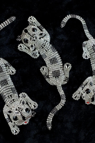 three 9" long clear & black "rhinestone" stylized leopard brooches against a black background