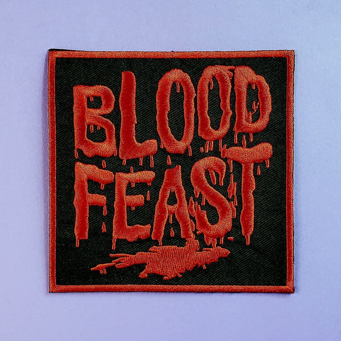 square embroidered patch featuring the red drippy blood style font logo of the 1963 film Blood Feast. On a black background with a red border 