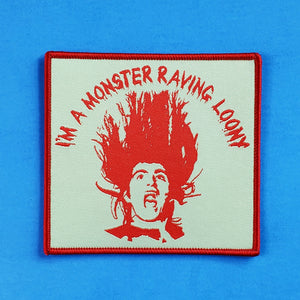A rectangular woven patch in bright red and mental hospital green featuring the face of 60s proto-shock rocker and head of the Official Monster Raving Loony Party, Screaming Lord Sutch!