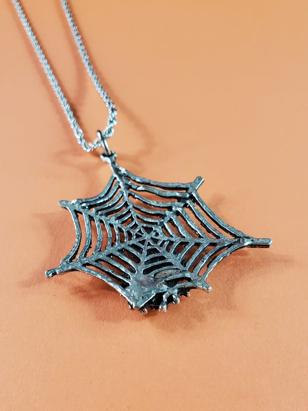 Large American pewter charm of a spiderweb with attached spider. Hanging from a stainless steel rope chain, showing back view