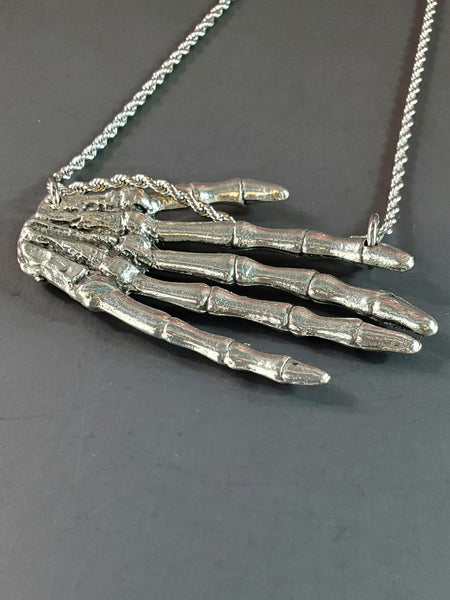 Large American pewter charm of a skeleton hand attached to a stainless steel rope chain , showing back view