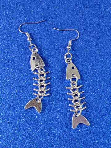 A pair of shiny silver metal dangle earrings with stylized charms in the shape of fishbones