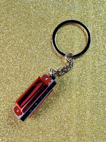 A red and silver metal harmonica charm on a split ring keychain