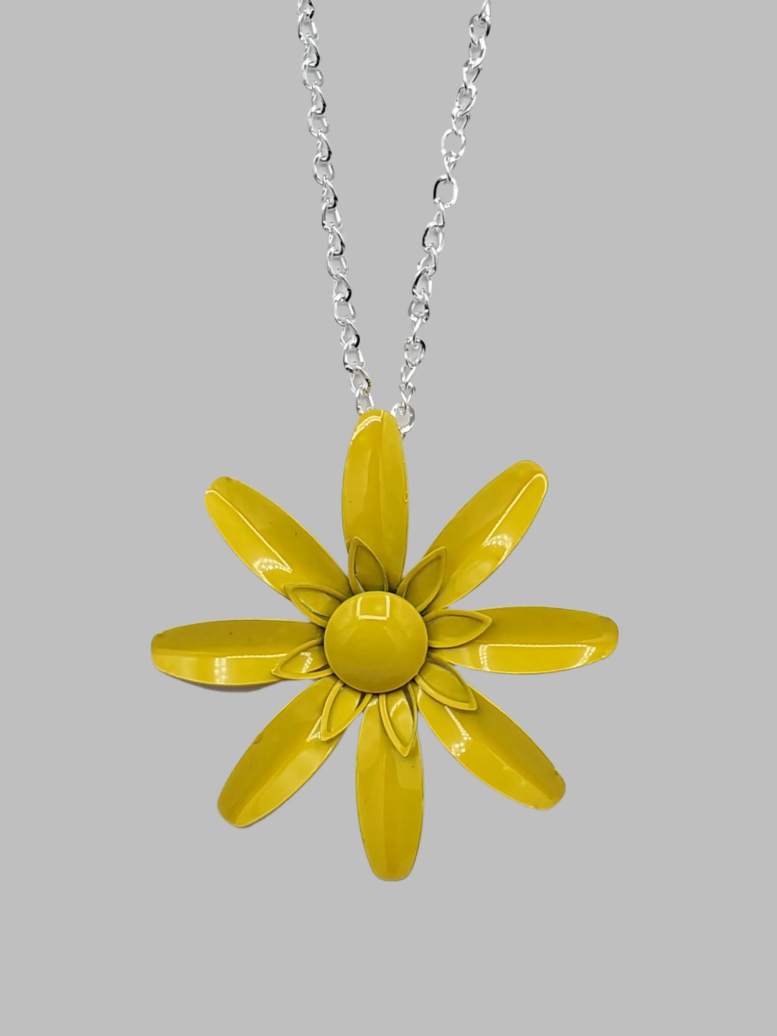 vintage-inspired metal daisy pendant in a shade of bright yellow on a 28” long shiny silver metal link chain