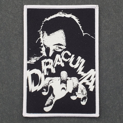 rectangular black woven patch with white border with illustration of Dracula reaching forward with one hand and "DRACULA" written in jagged new wave font