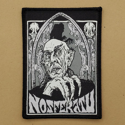 black woven patch with embroidered border and black and white line illustration of Max Schreck as Count Orlok surrounded by an ornate border and skulls