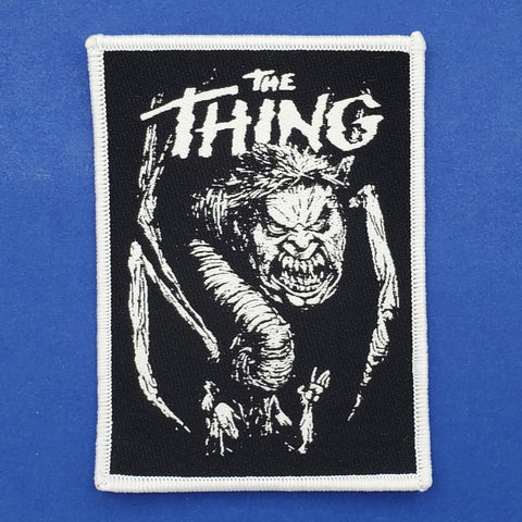 black woven patch with white embroidered border of white illustration of the alien from the movie The Thing