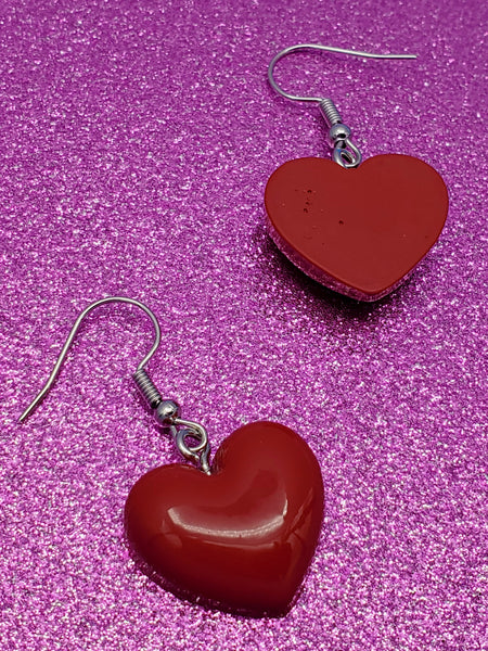 pair of red acrylic puffy heart dangle earrings. showing back view of one