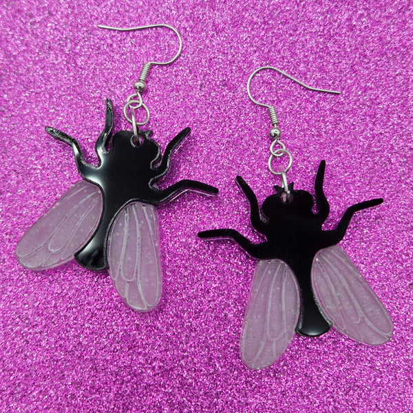 pair of laser cut acrylic earrings in the shape of house flies with black bodies and matte white etched wings