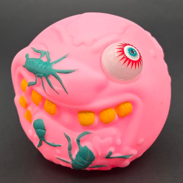 Pink monster with one red eye and green bugs toy ball on a black background