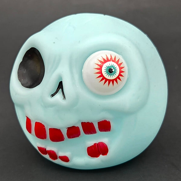 Light blue skull-shaped ball with a single eye on a dark background
