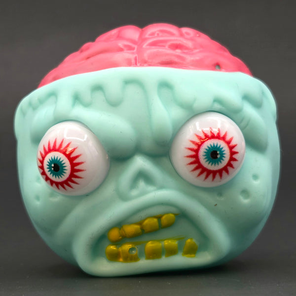Light green monster with exposed brain and red eyes toy ball on a dark background