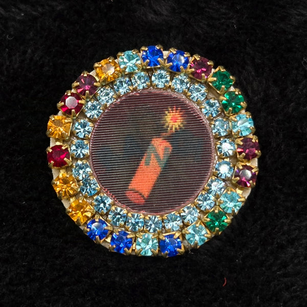 round lenticular dynamite/'BANG!' brooch with colorful rhinestone border, shown on a black background