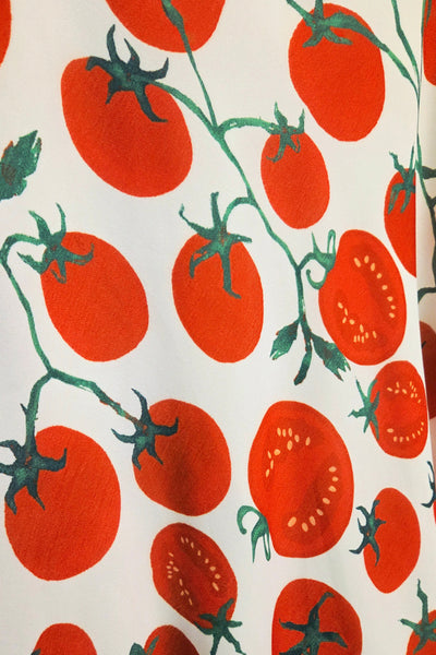 Pattern of red tomatoes with green stems on a white background