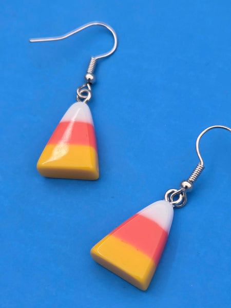 Candy corn-shaped earrings on a blue background