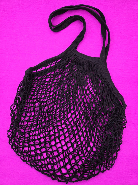 Black cotton mesh shopping bag with a handle on a magenta background