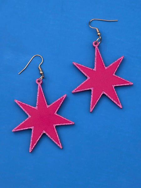 Magenta laser-cut acrylic starburst dangle earrings with a matching glitter border 