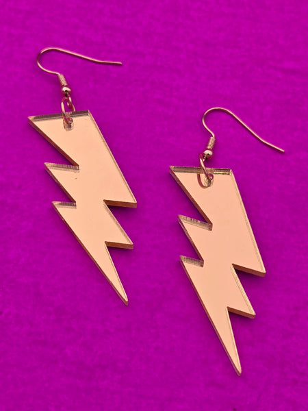 gold mirrored acrylic lightning bolt earrings on a purple background