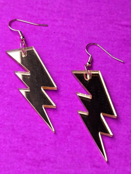 gold mirrored acrylic lightning bolt earrings on a purple background