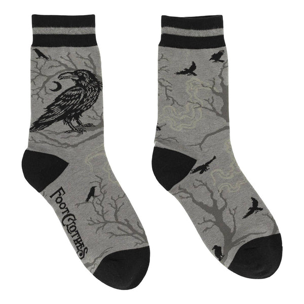 pair of medium grey cotton blend crew socks with solid black toes and heels & striped black and grey cuffs. All over pattern of a large crow on the outer ankle with a tree in the background with crescent moons and small flying crows in black. Shown flat