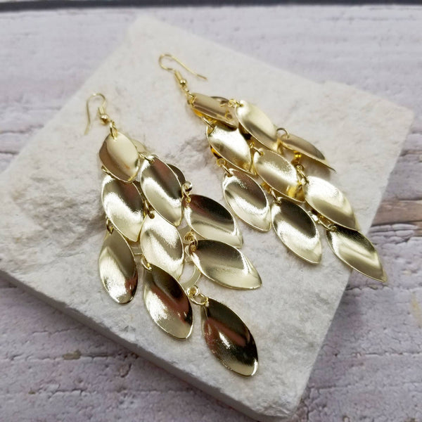 gold metal dangle earrings of stylized leaf shapes staggered together with jump rings
