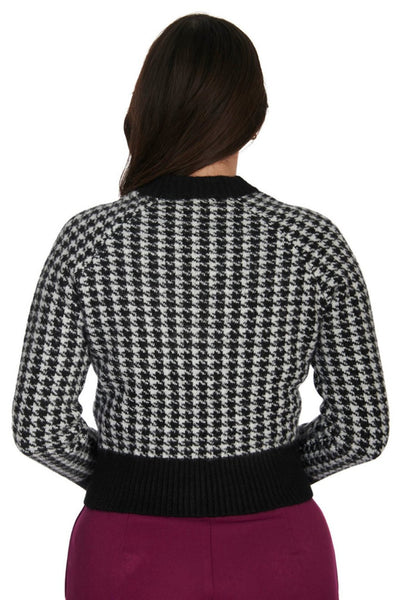 retro style long sleeve waist length button-up cardigan in a knitted black &amp; white houndstooth pattern with solid black ribbed knit waistband, cuffs, and stand-up collar. shown from the back on a model