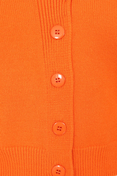 orange retro style shawl collar long sleeve waist length cardigan, showing a cropped close up of the button placket