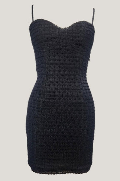 Black waffle knit bodycon mini dress with adjustable spaghetti straps, vertical seaming, and black lace trim at bodice and  bottom hem. Shown from front