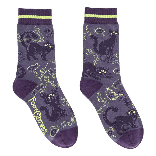 pair of cotton blend unisex crew socks in medium purple with dark purple toes & heels and striped purple and light lime green cuffs. Allover design of dark purple cats with green eyes and large third eyes surrounded by wispy ghosts and spirits. Shown flat