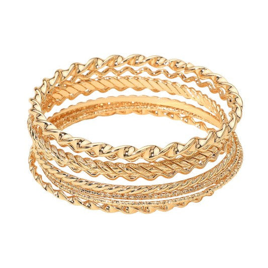 set of eight various textured wavy and twisted gold metal bangles shown stacked