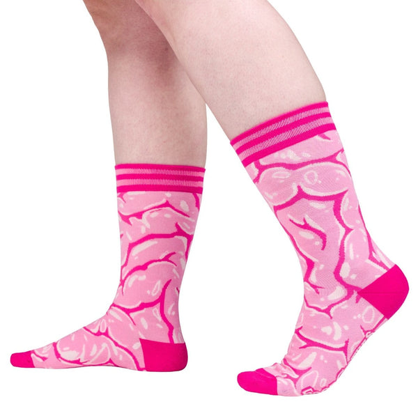 cotton unisex crew socks with allover pattern of pink and white brain matter, with pink striped cuffs and solid pink heels & toes. Shown worn by a model from the side