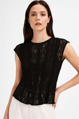 model wearing a black floral patterned lace top with round neckline, short cap sleeves, and vertical ruffle details. Shown from front