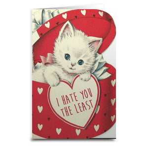 Rectangular note card with printed image of a vintage-style white kitten inside of a heart patterned heart-shaped box holding a valentine that reads “I HATE YOU THE LEAST”