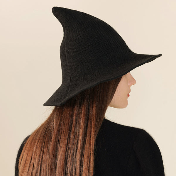 Woman wearing a black textured ribbed knit witch hat against a plain background. Shown from back