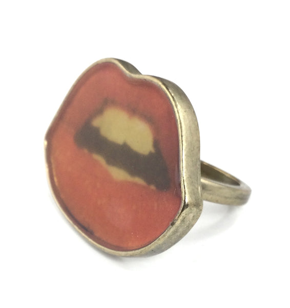 antiqued gold metal ring with photographic image of pair of red lips with teeth showing. Shown from side
