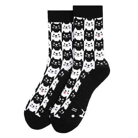 black ankle socks with a knit-in pattern of black and white cats alternating to make a checker-style pattern. They all have cartoony stylized faces and some have pink tongues sticking out. The bottom of each sock is black with white cat face illustration. Shown flat