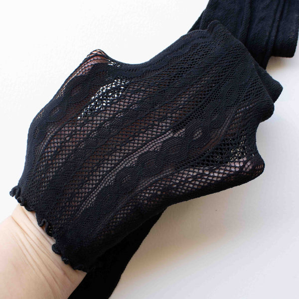 black cotton knit knee high socks with rolled top band in a classic black geometric openwork design. Shown held taut to display knit in pattern