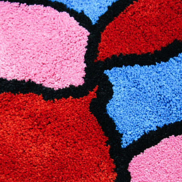 up close shot of red, pink, and blue sections of rug outlined in black