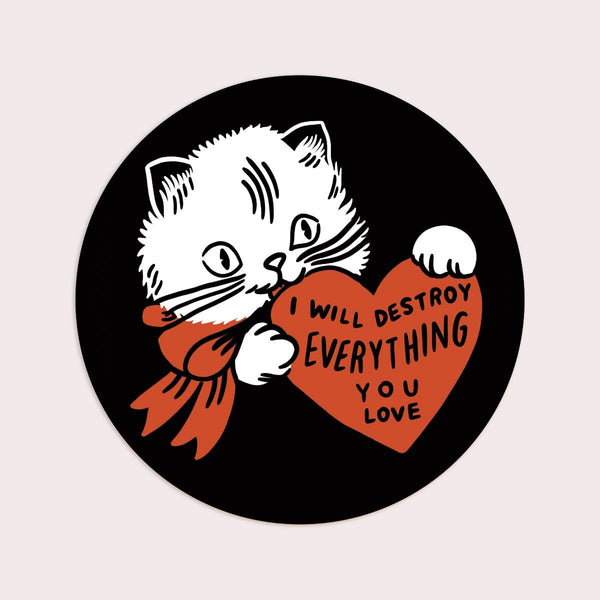 round die-cut vinyl sticker of white kitten with red bow holding red heart with message "I Will Destroy Everything You Love" on a black background