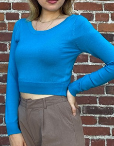 long sleeve bright turquoise blue sweater featuring a wide round neckline and cropped length. shown on model.