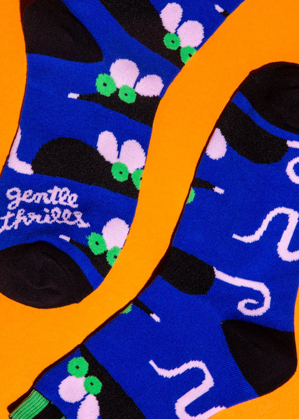 cotton crew socks with black, lime green, and light pink rats on a cobalt blue background with black and green striped cuffs & black heels and toes. Shown on bright orange background