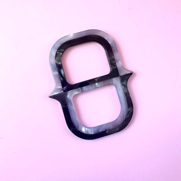 layered acrylic pearly black and grey scarf slide in the shape of an oversized chain link. Shown flat on pink background